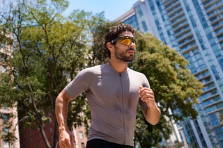Runner on a city street between glass towers wearing camera glasses
